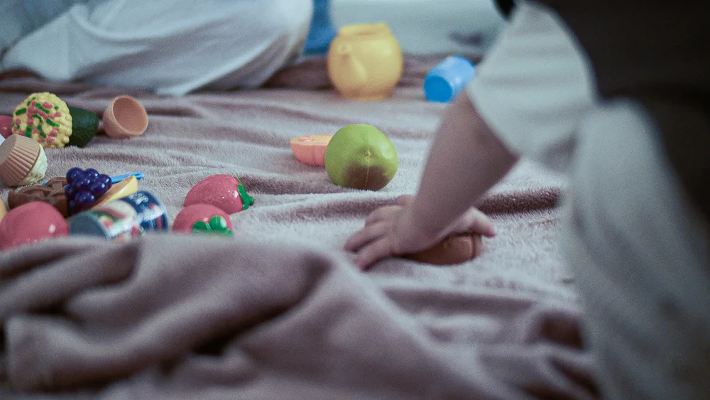 A child's hands playing with sensory toys on a soft rug