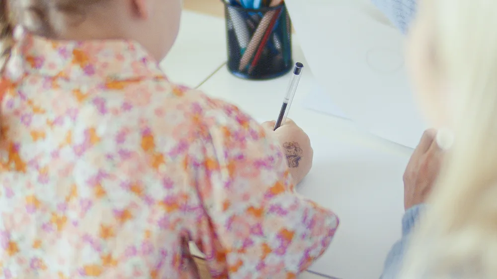 A child practising drawing at a desk in the therapy room