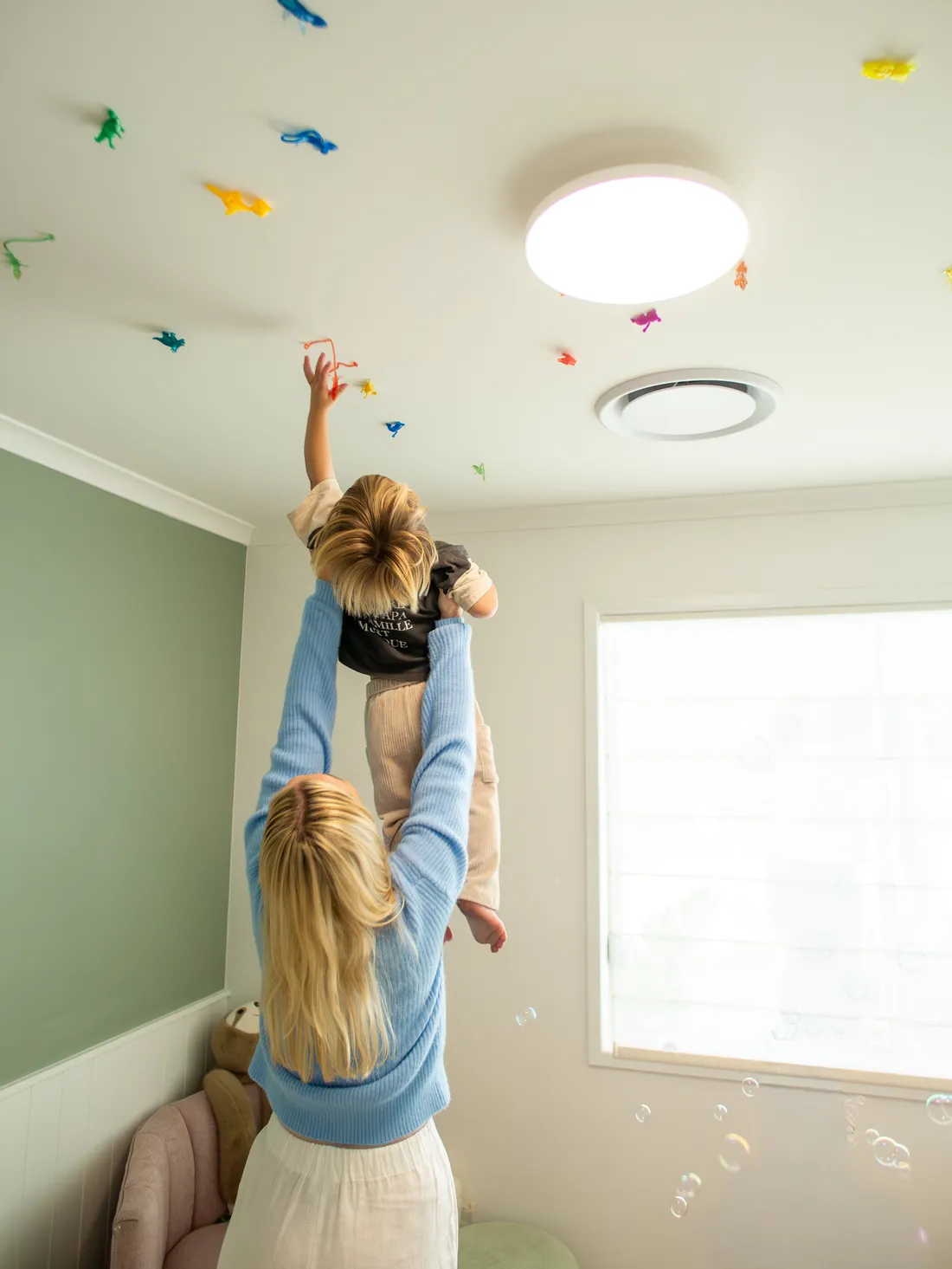 A child reaching up towards star decorations on the ceiling